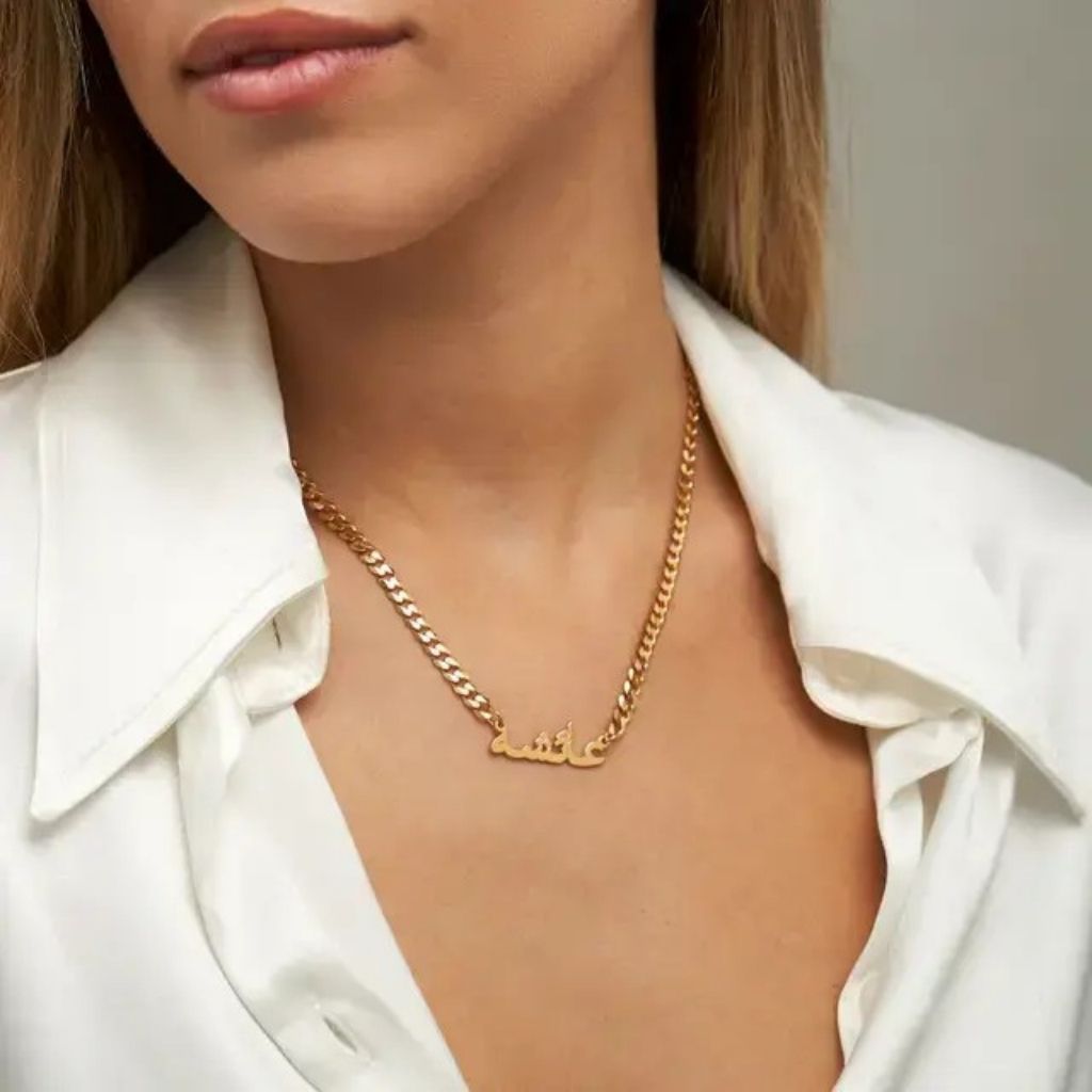 Gold chain necklace worn by a person with a white shirt