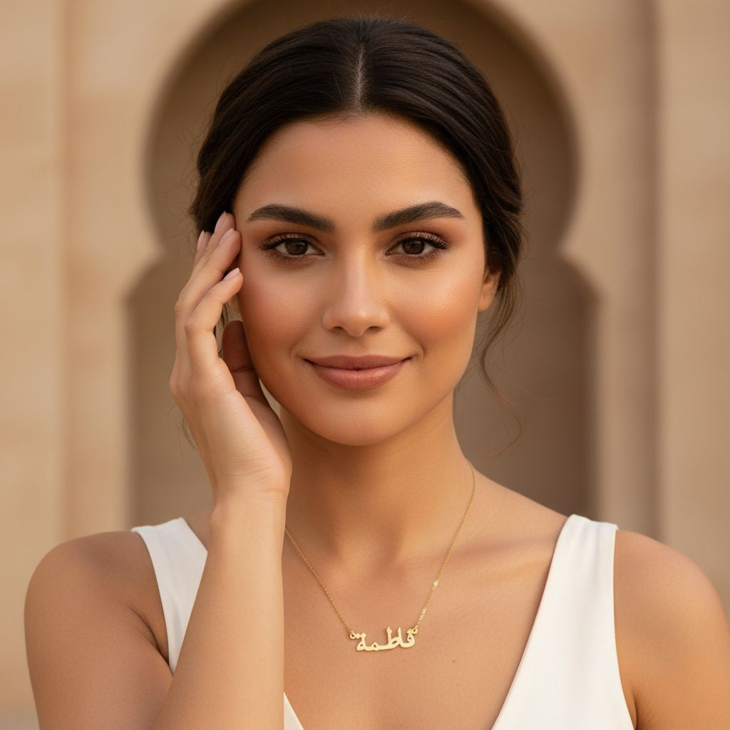 Woman wearing a gold necklace with a nameplate against a beige background