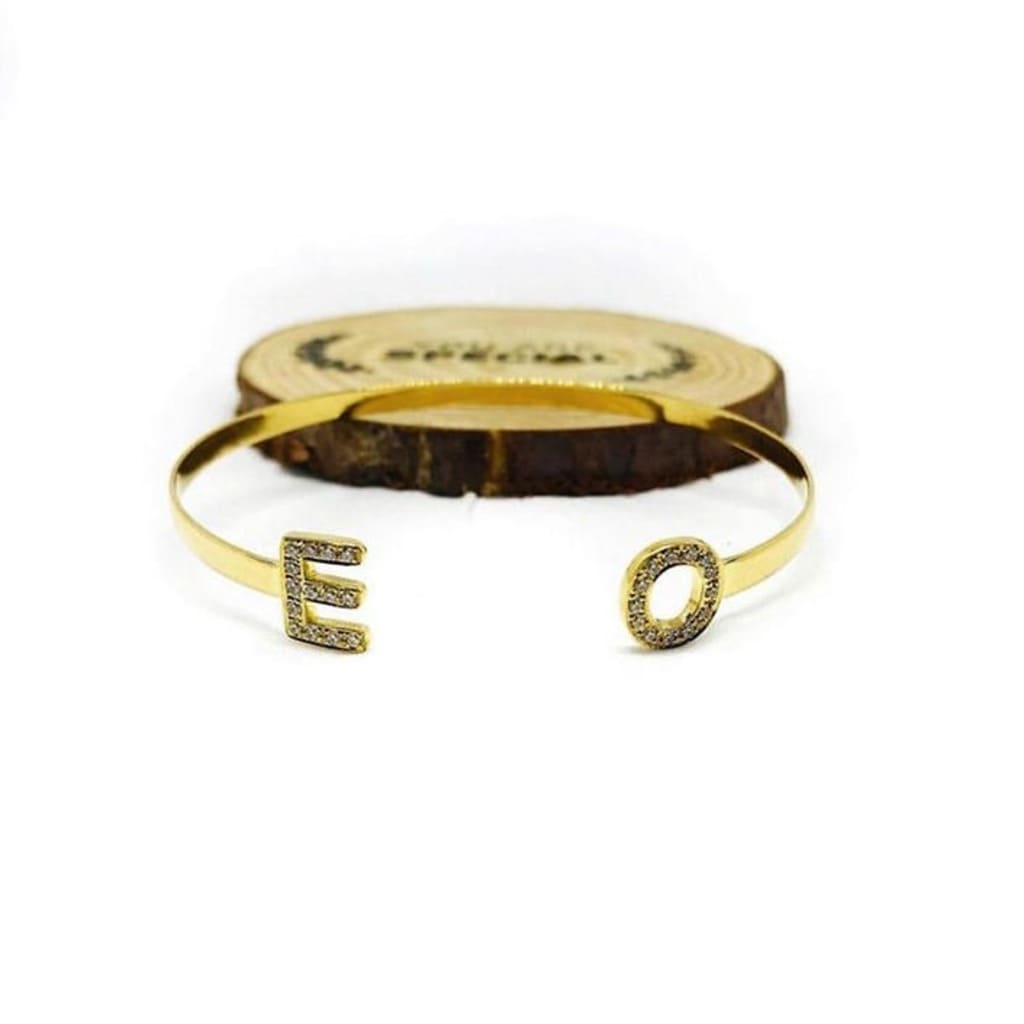 Gold bracelet with letter 'E' and 'O' on a white background