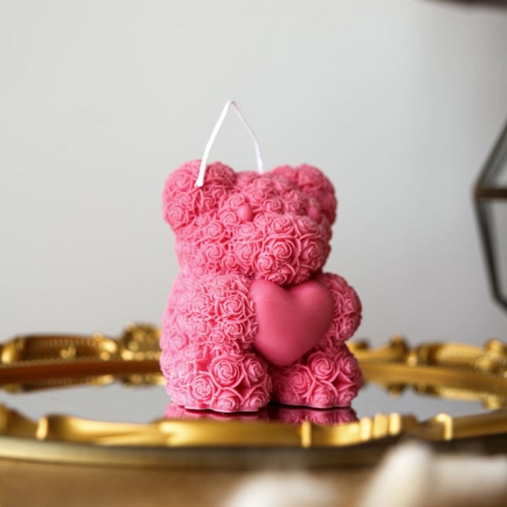Pink teddy bear candle with rose patterns on a gold surface