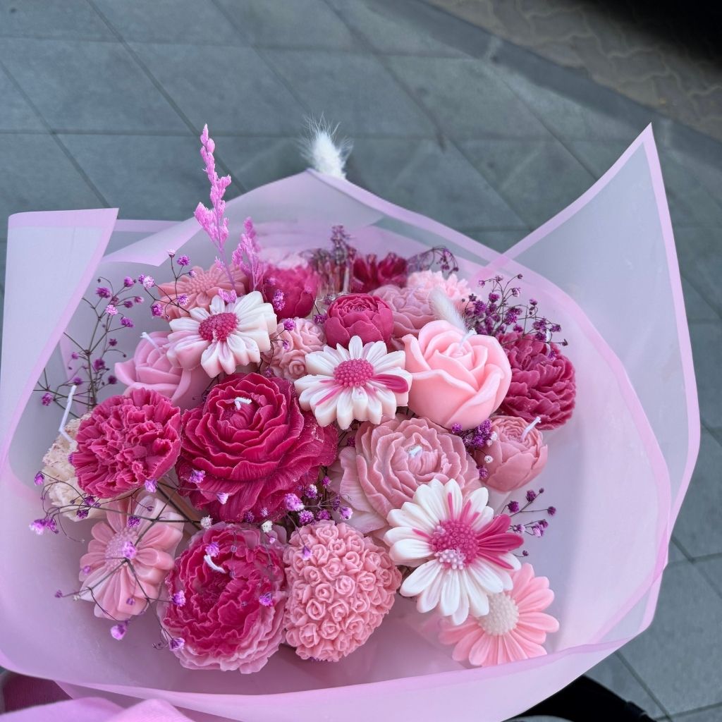 Bouquet of pink and white flowers wrapped in clear plastic on a gray pavement background