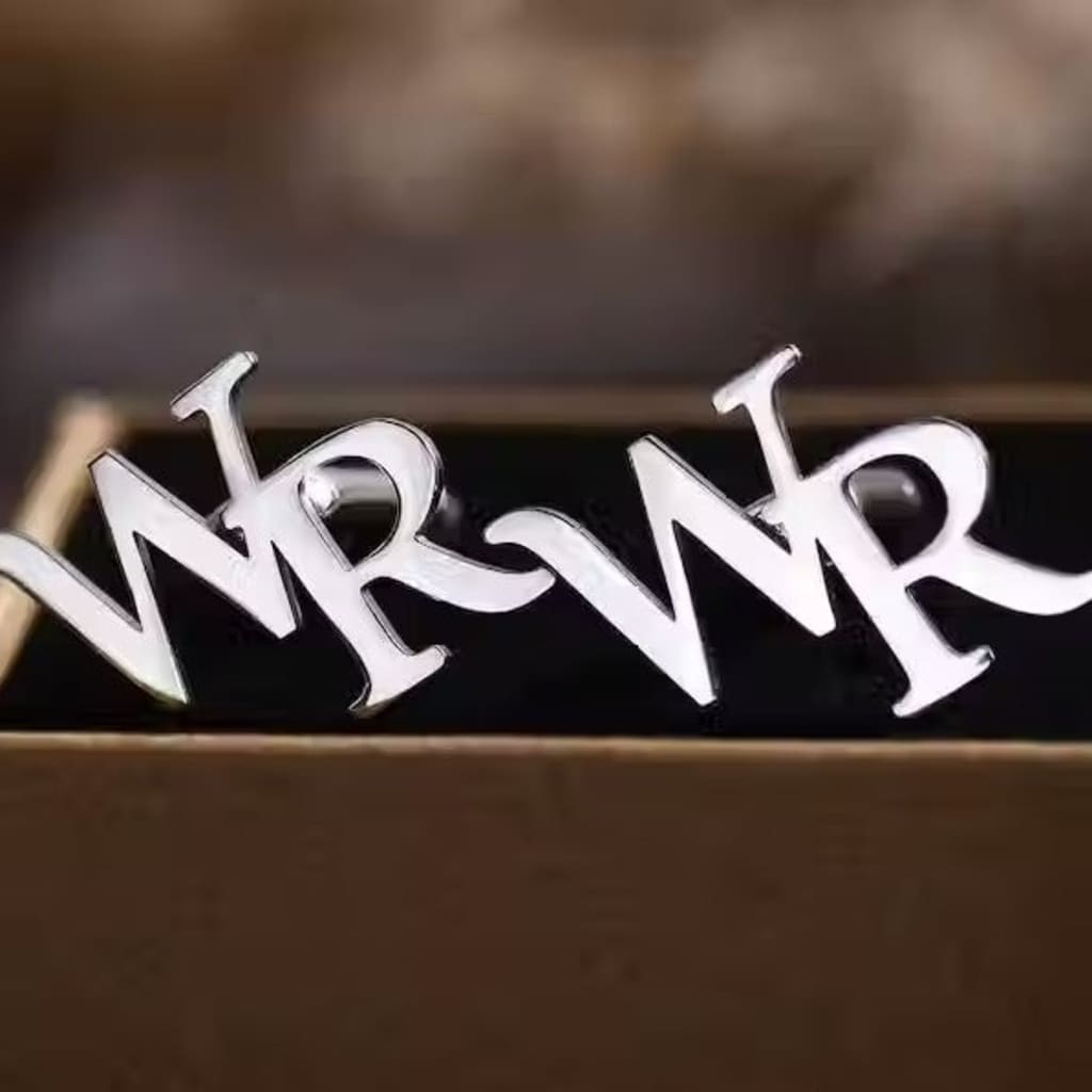 Silver 'MR' cufflinks on a wooden surface with a blurred background