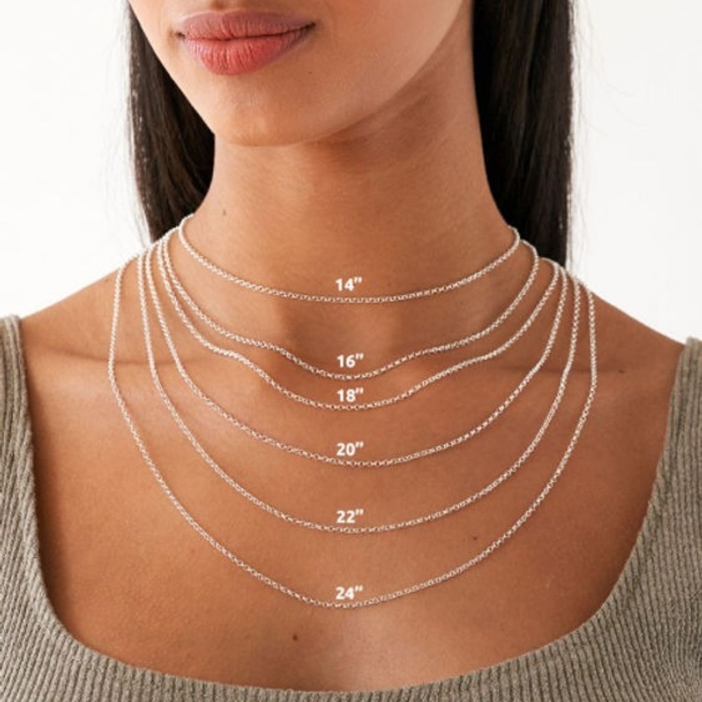 Silver necklaces of different lengths displayed on a person's neck.