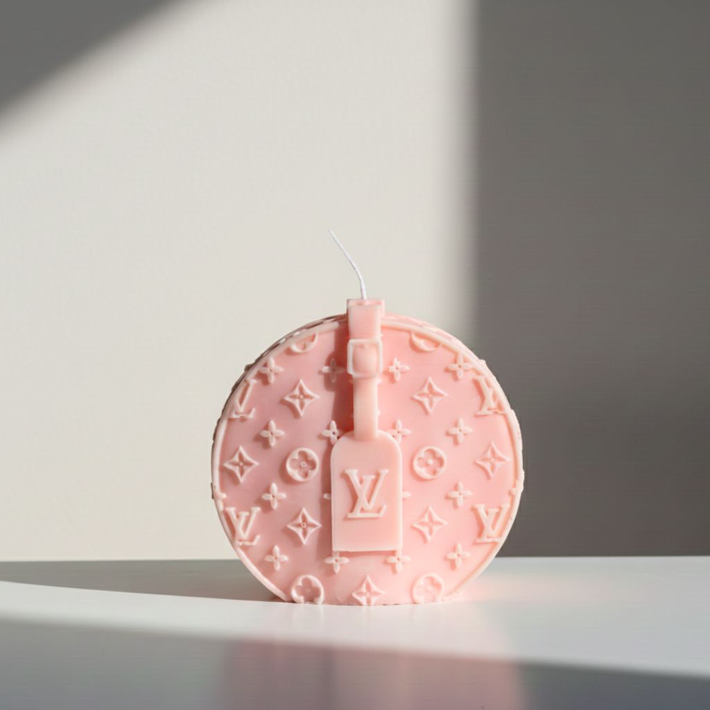 Pink round candle with Louis Vuitton logo on a white surface