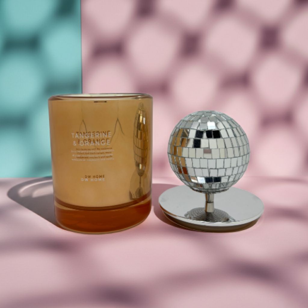 Candle with a decorative mirror ball on a pastel background