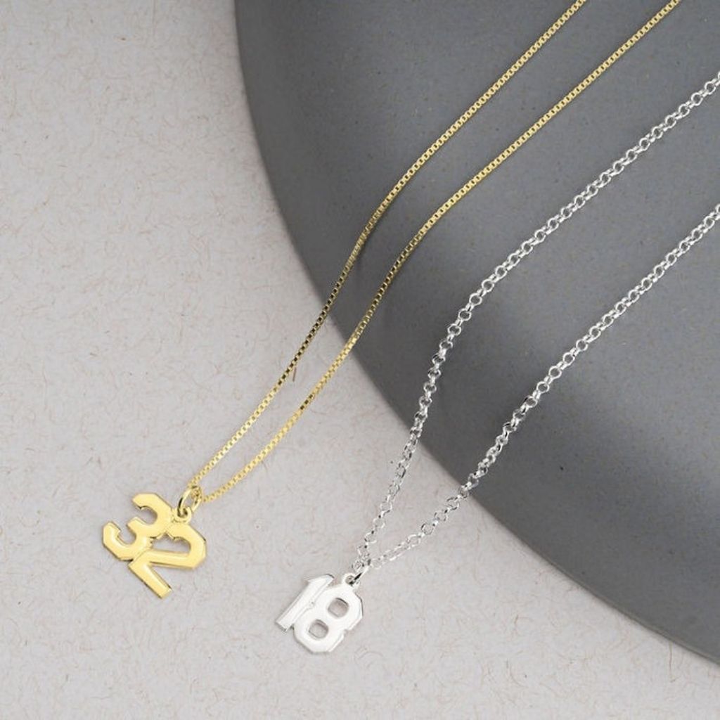 Two necklaces with unique pendants on a neutral background