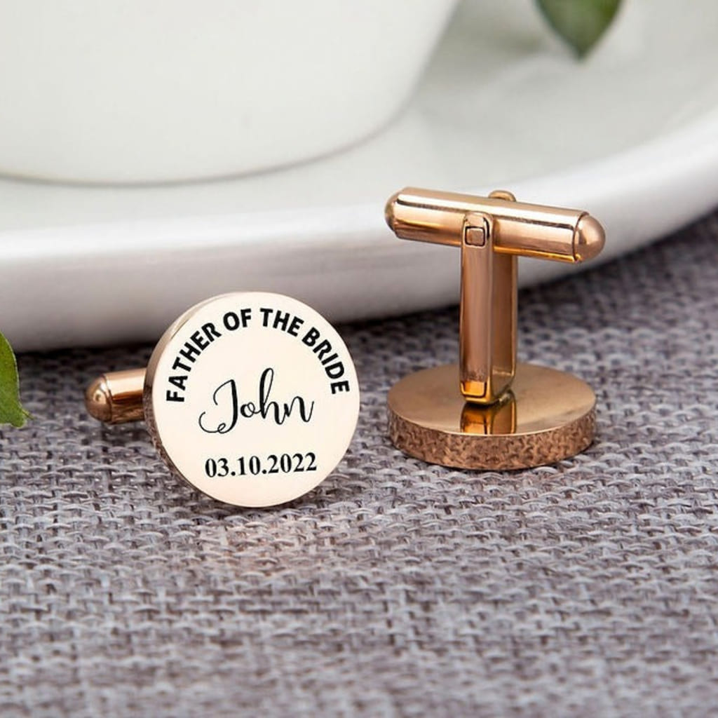 Rose gold cufflinks with engraved text on a textured surface