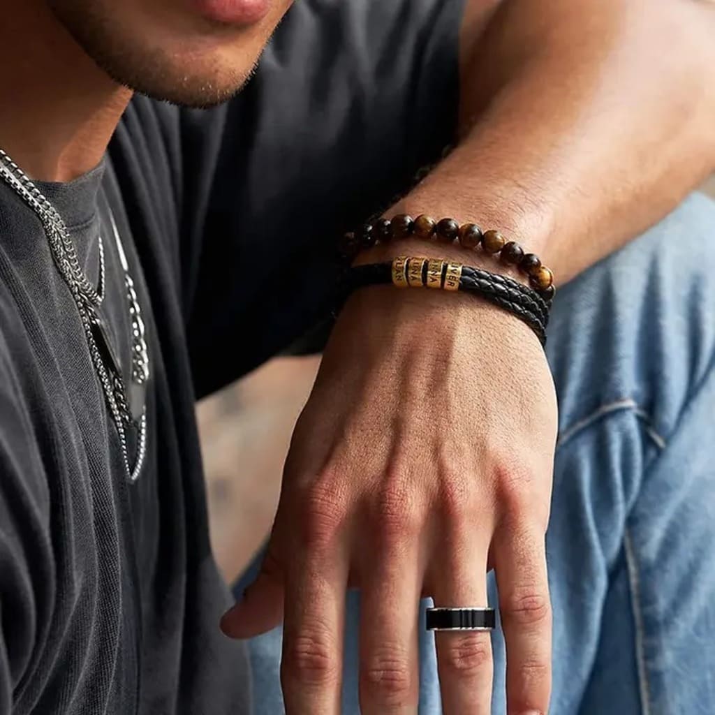 Close-up of a person's wrist with multiple bracelets and a ring.