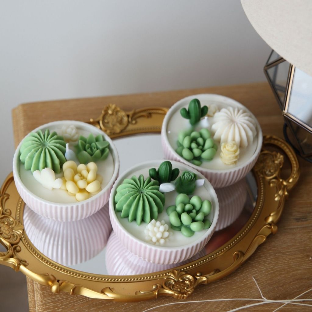 Decorative candles with succulent designs on a gold tray