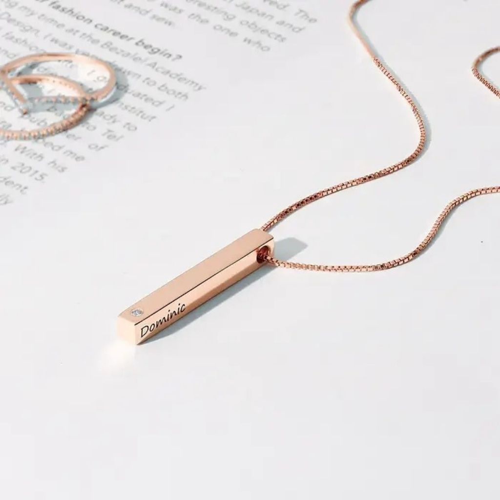 Rose gold necklace with a bar pendant on a white surface