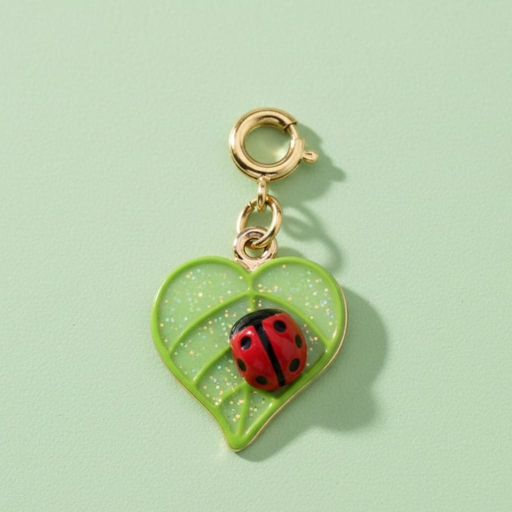 Green heart-shaped charm with a ladybug on a light green background