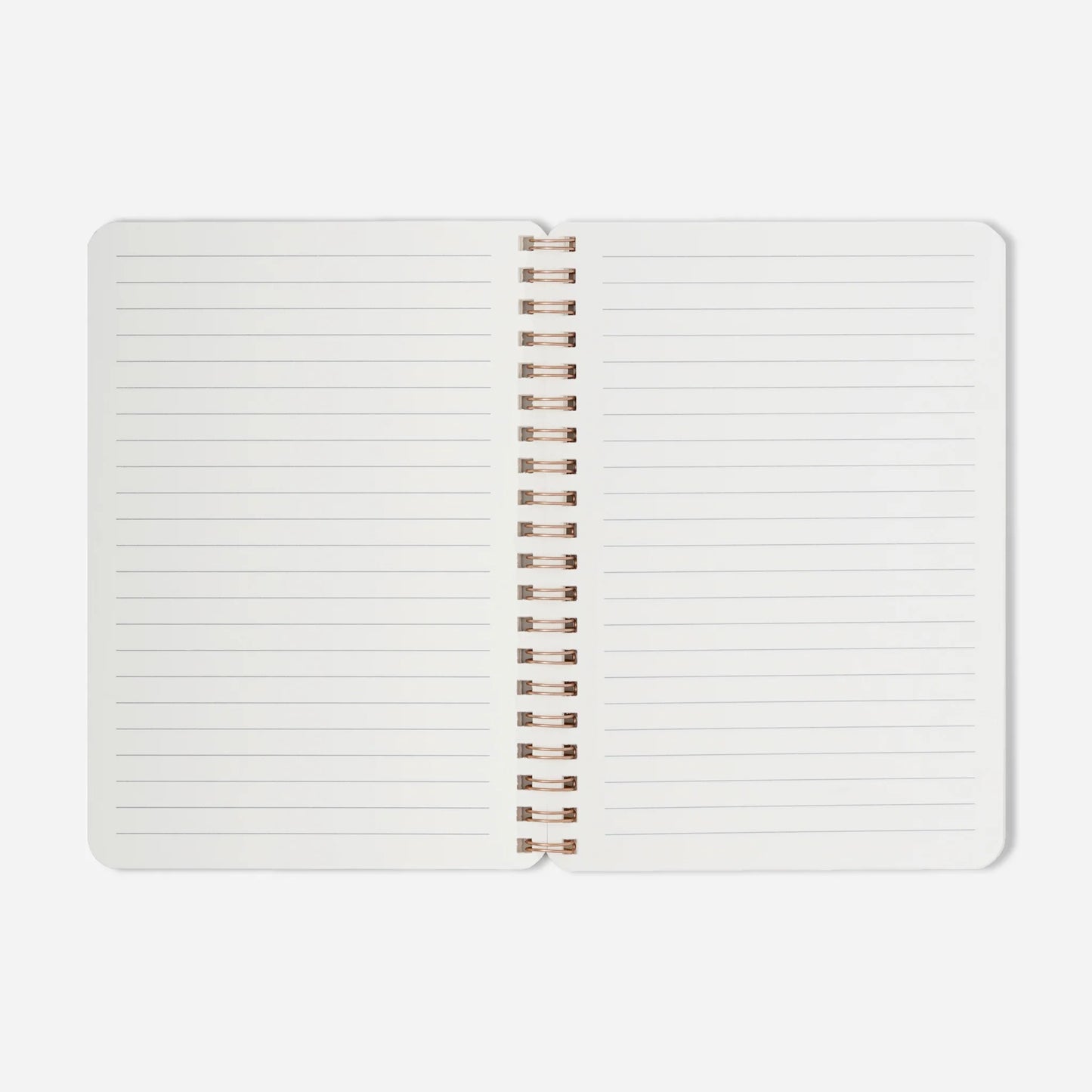 Open notebook with white pages and rose gold spiral binding on a light gray background