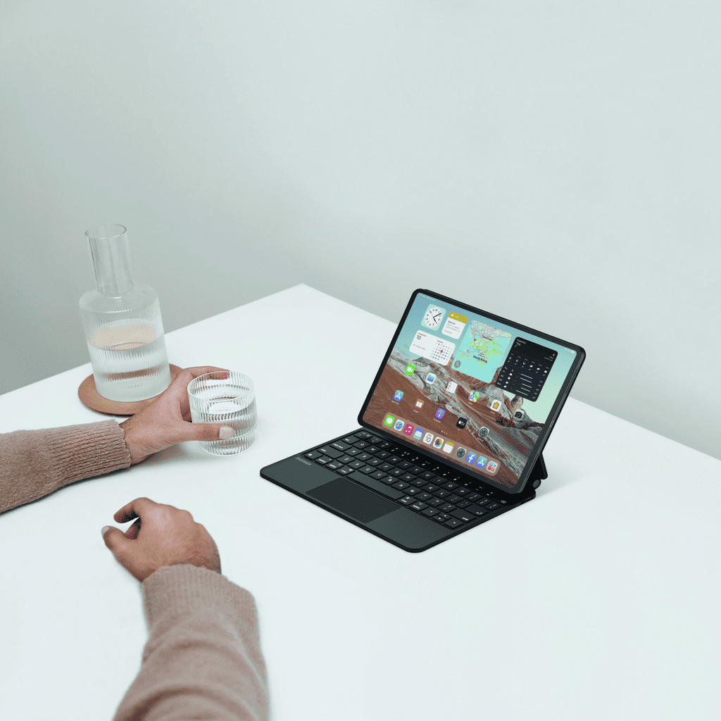 Person using a tablet with a keyboard on a white surface