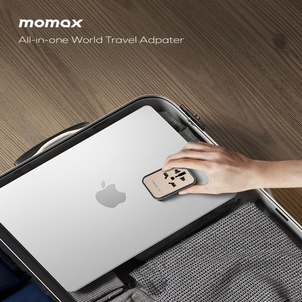 Momax all-in-one world travel adapter being used with an Apple device on a wooden surface.