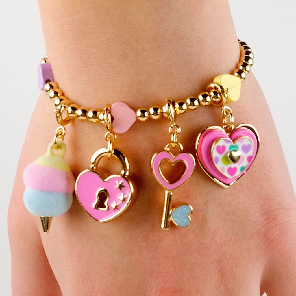 Bracelet with heart and key charms on a wrist against a white background