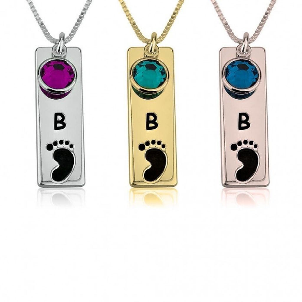 Three necklaces with rectangular pendants featuring initials 'B' and footprints, in silver, gold, and rose gold.