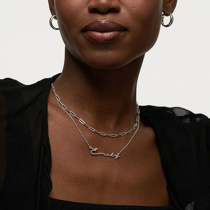 Woman wearing a silver necklace with 'Emily' engraved on it against a neutral background