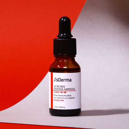 J'sDerma skincare ampoule bottle with dropper on a red and gray background