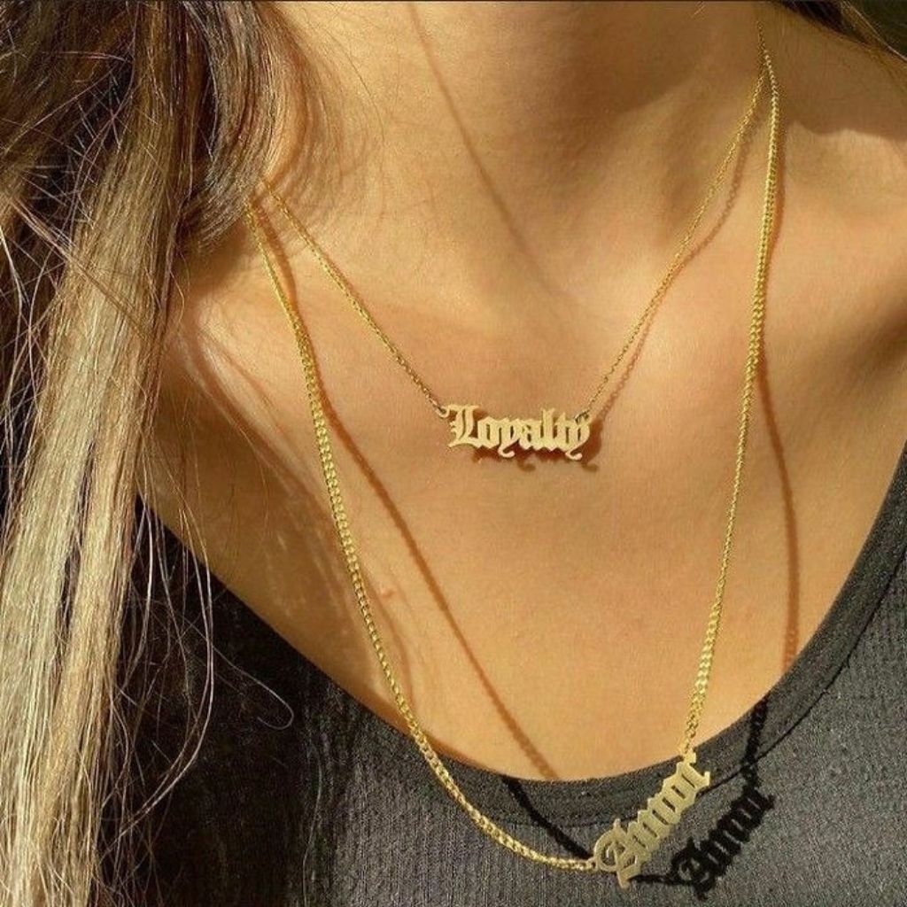 Gold necklace with 'Loyalty' pendant on a person wearing a black top.