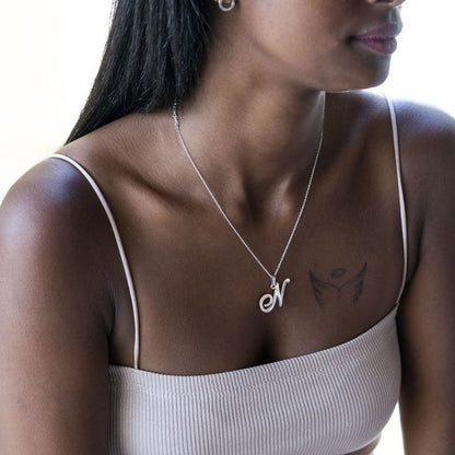 Woman wearing a silver necklace with a pendant, close-up on neck and chest.
