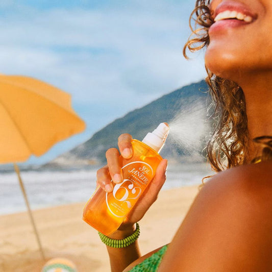 Woman applying sunscreen on a beach with a scenic background