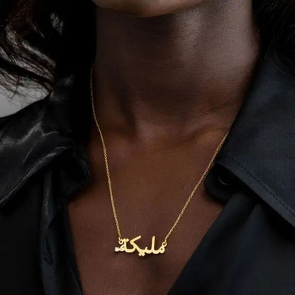 Gold necklace with Arabic script worn by a person against a dark background