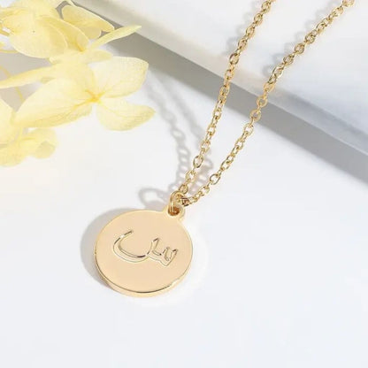 Gold necklace with a round pendant on a white background with yellow flowers.
