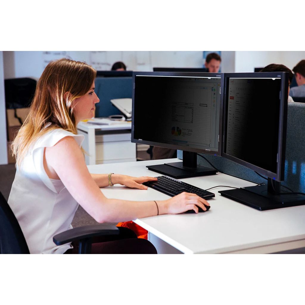 Person working at a desk with two computer monitors in an office setting.