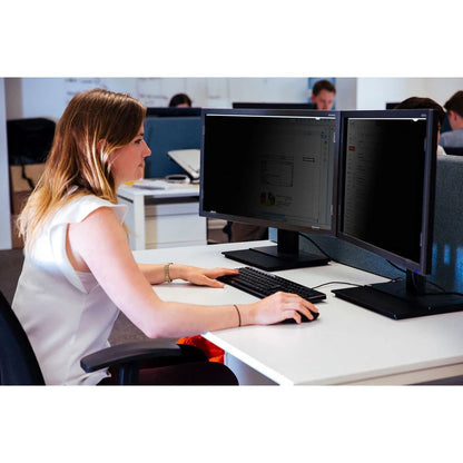 Person working at a desk with two computer monitors in an office setting.