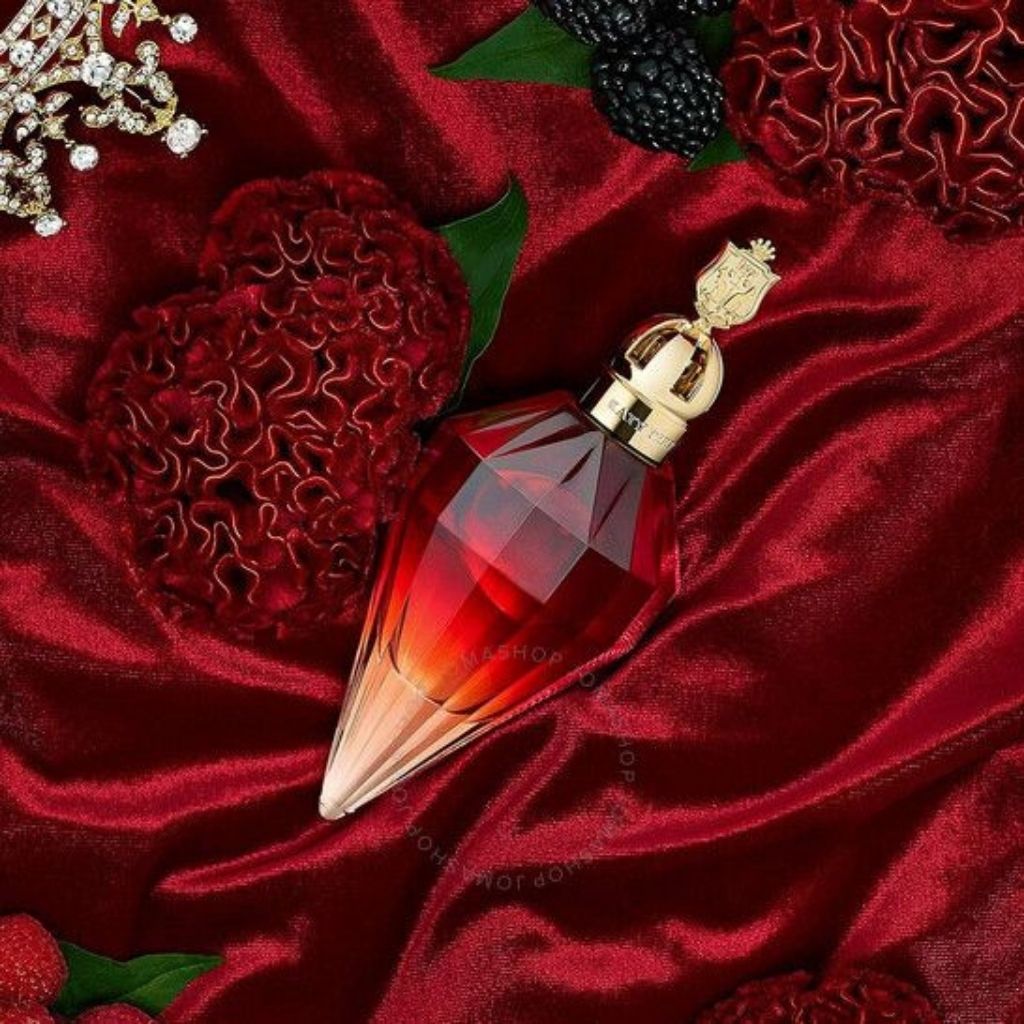 Red and gold perfume bottle on a red fabric background with berries and flowers.