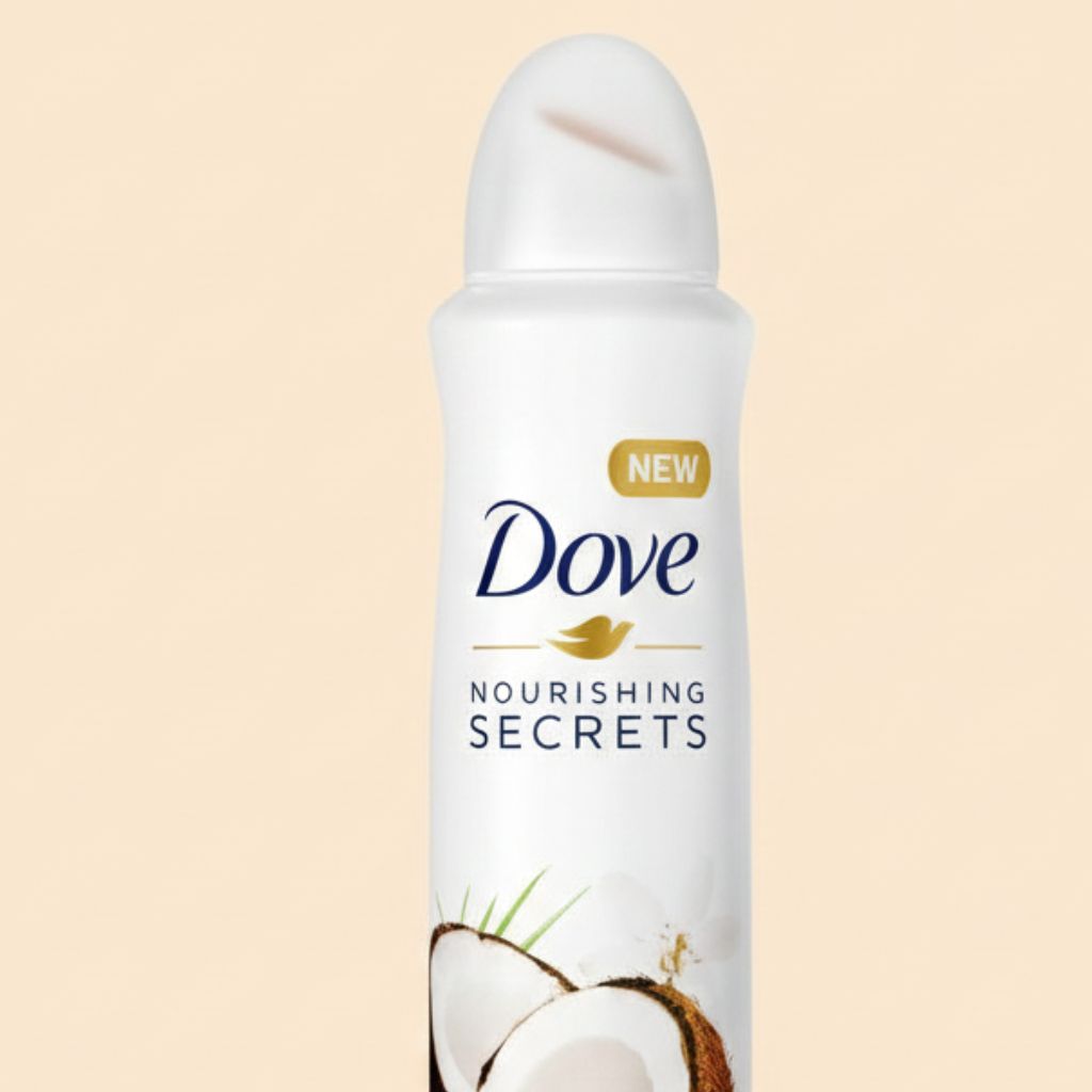 Dove deodorant spray bottle with coconut imagery on a beige background