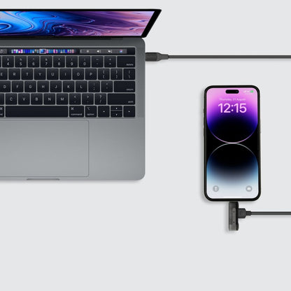 Laptop and smartphone connected by a cable on a light gray background