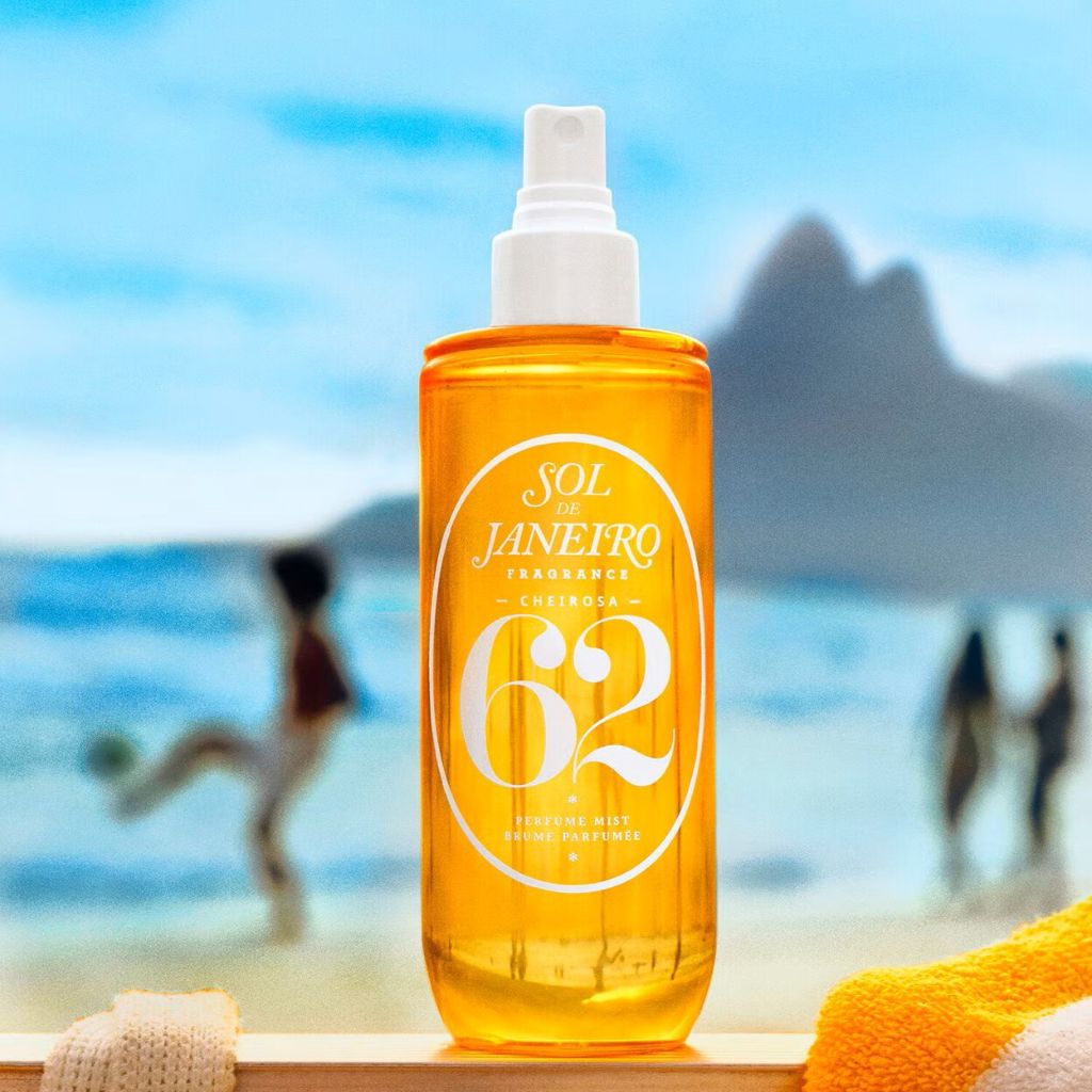 Orange spray bottle with 'Sol de Janeiro' branding on a beach background