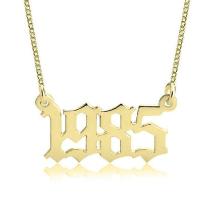 Gold '1985' necklace on a white background