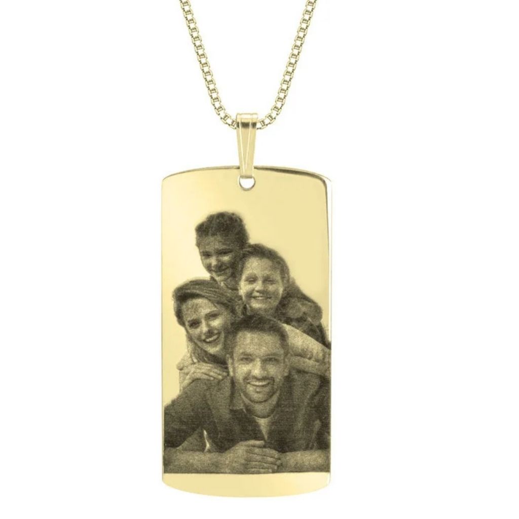 Gold pendant with a photo of four people engraved on it, on a white background