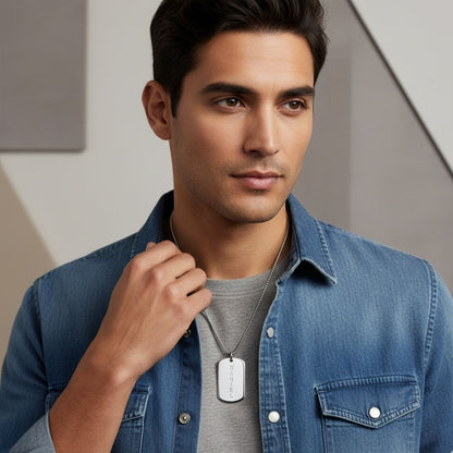 Man wearing a denim jacket with a necklace featuring a dog tag.