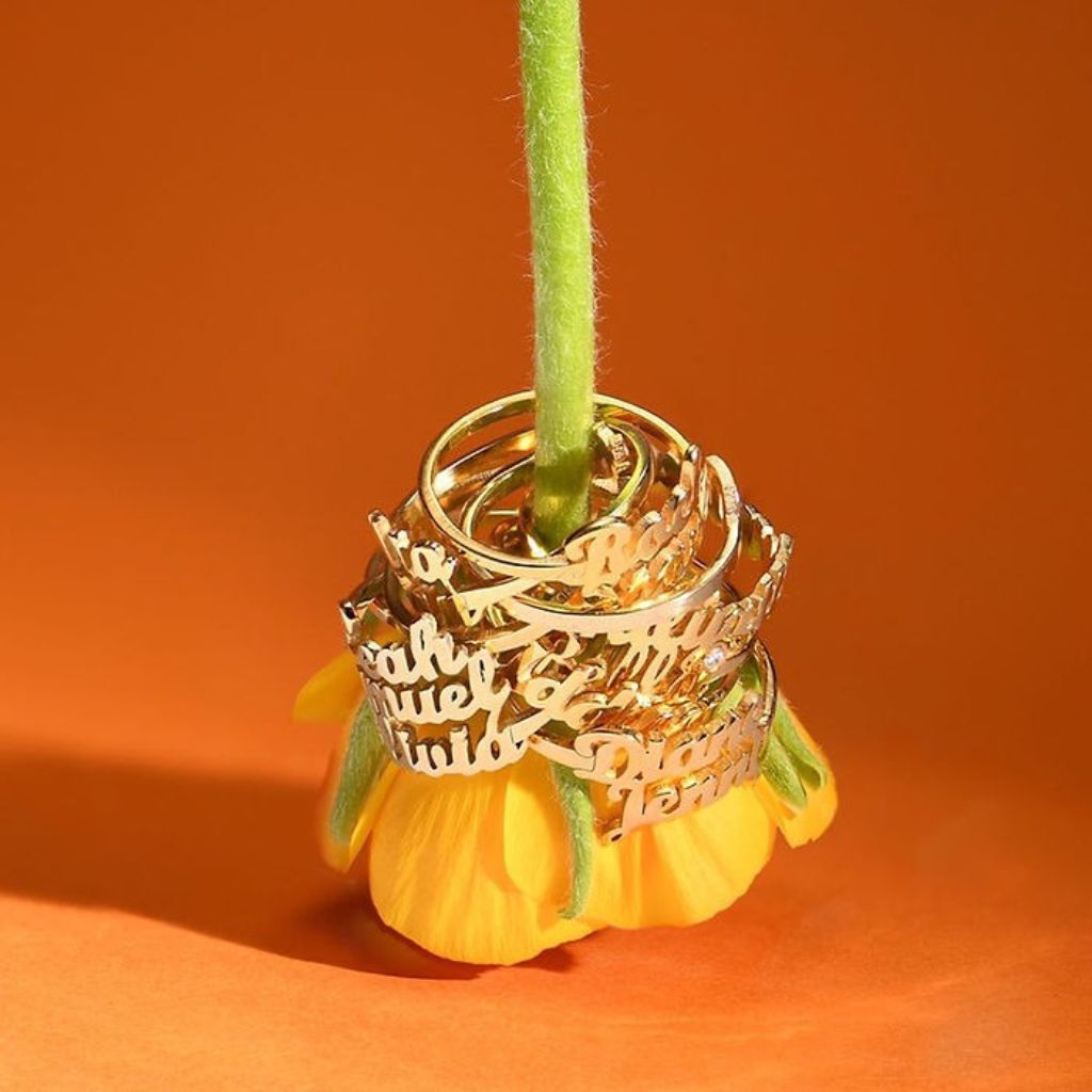 Gold rings stacked on a yellow flower against an orange background
