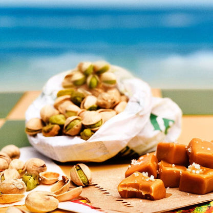 Pistachios and caramels on a wooden board with a blurred beach background