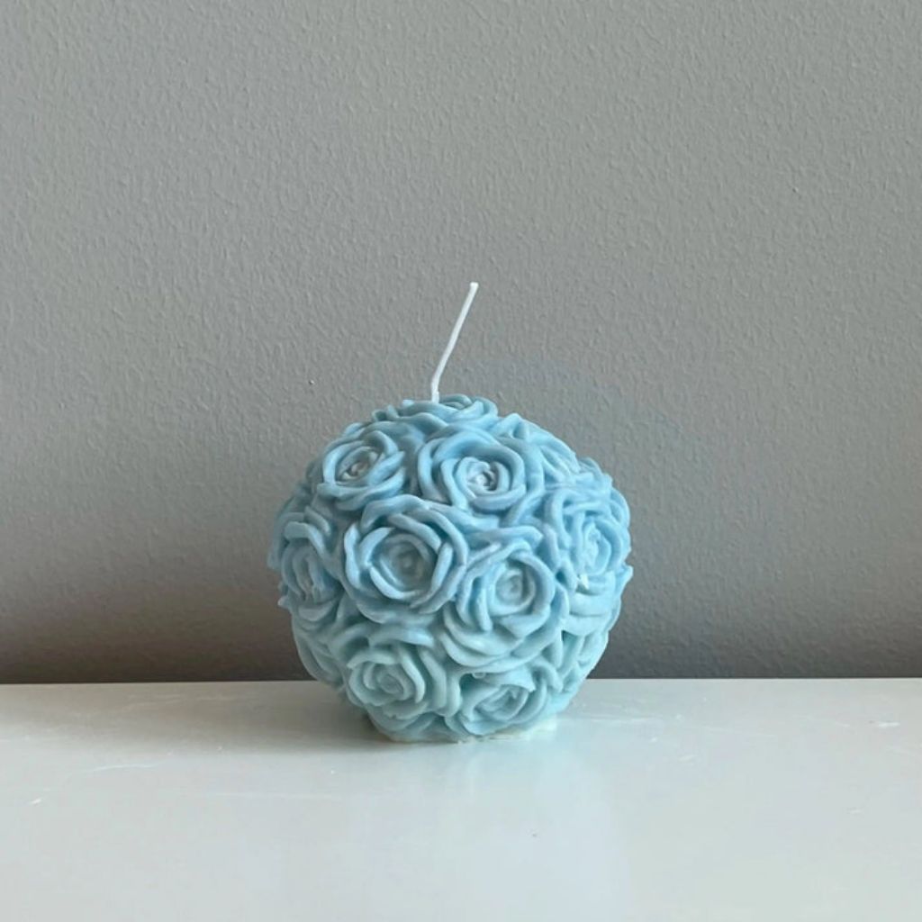 Blue spherical candle with rose pattern on a gray background