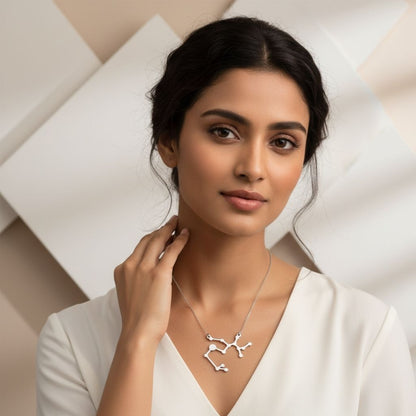 Woman wearing a silver necklace against a neutral background