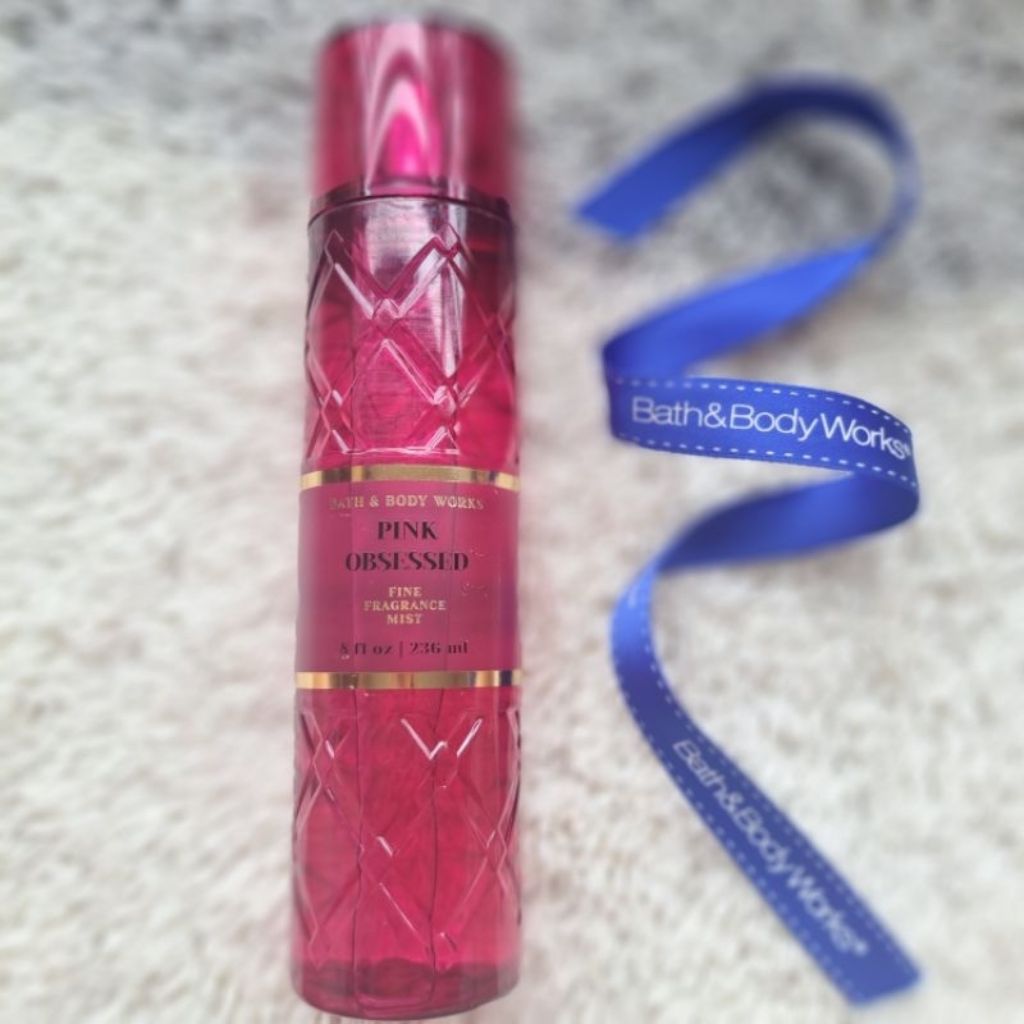 Bath & Body Works Pink Obsessed perfume bottle with a blue ribbon on a textured surface