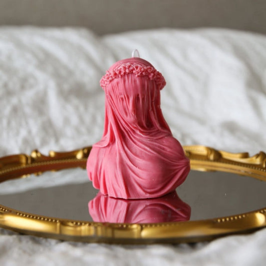 Pink figurine with a headscarf on a reflective surface with a blurred background