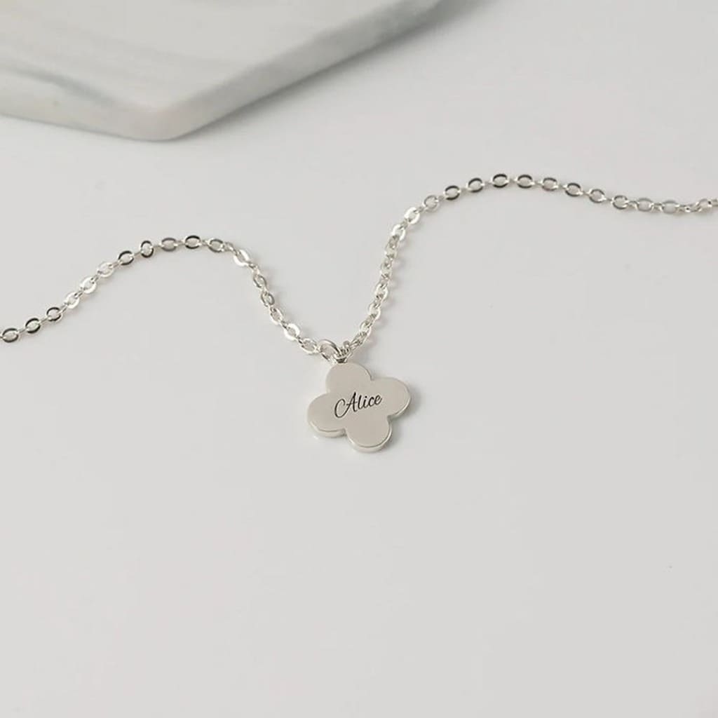 Silver necklace with a clover-shaped pendant on a light gray background