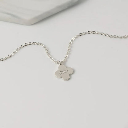 Silver necklace with a clover-shaped pendant on a light gray background