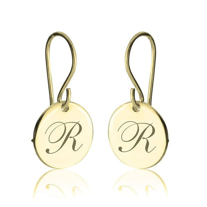 Gold earrings with 'R' engraving on a white background