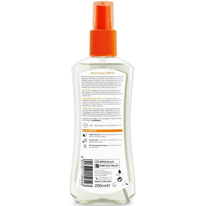 Clear spray bottle with orange nozzle on a white background