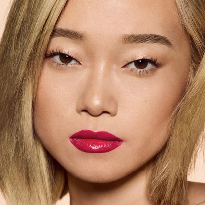 Close-up of a person with bright pink lipstick on a neutral background