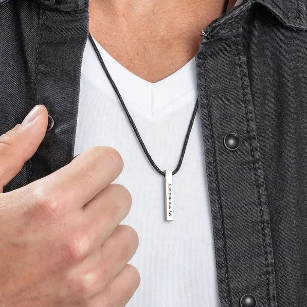 Person wearing a black necklace with a pendant, adjusting it.
