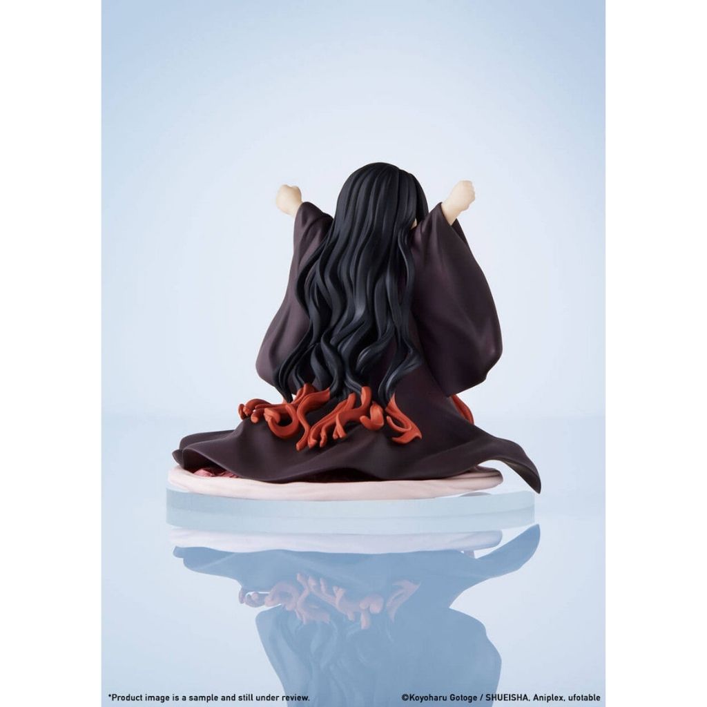 Figurine of a character with long dark hair and red accents on a light blue background