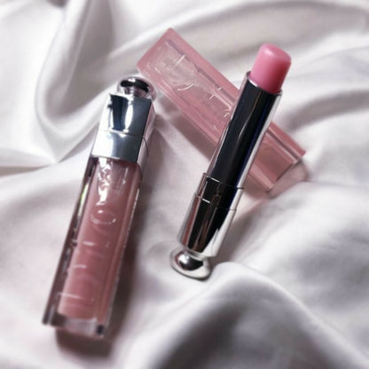 Two lip products, a lip gloss and a lipstick, on a white fabric background.